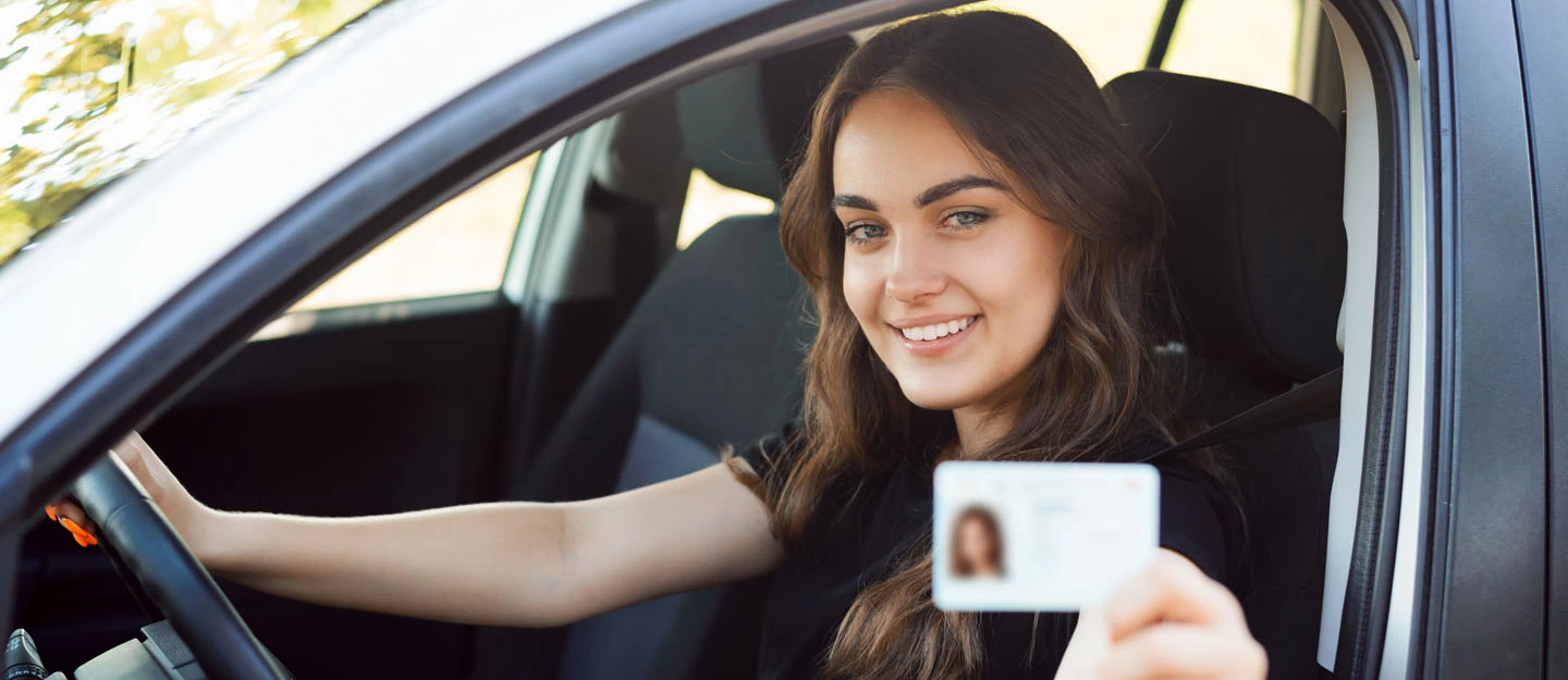 Smiling woman in a car showing her international driving permit